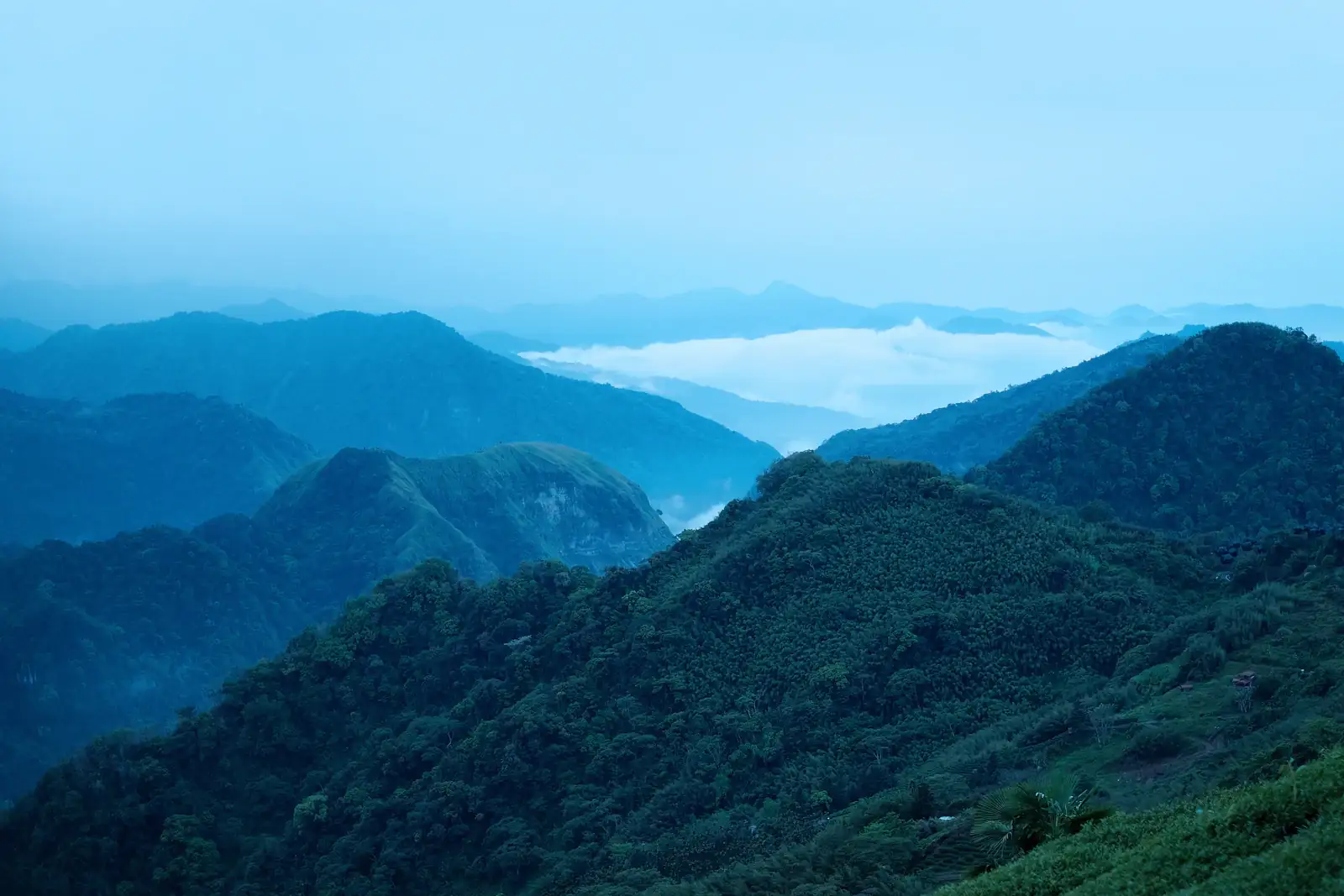 Green mountain ranges under a soft white sky