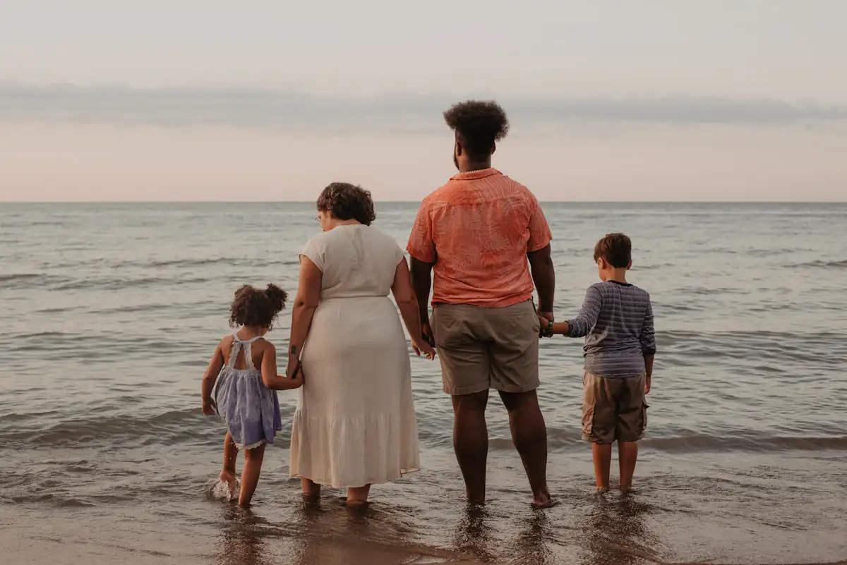 A family walking together along the shoreline in warm evening light