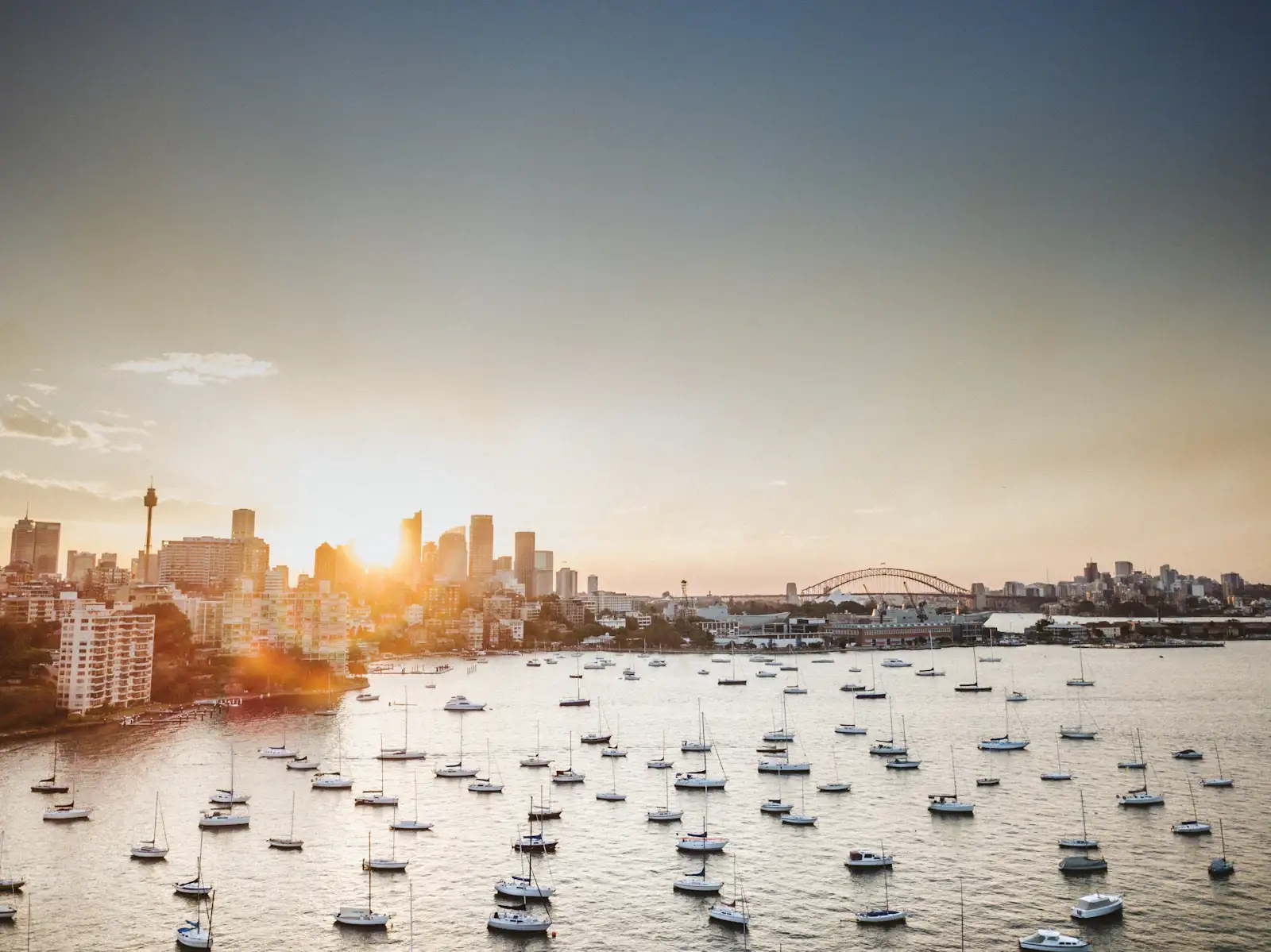 Sunrise over Sydney Harbour, with the city skyline and the Harbour Bridge beyond moored boats